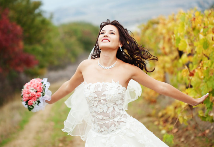 Braut mit Blumenstrauß vor einem Feld