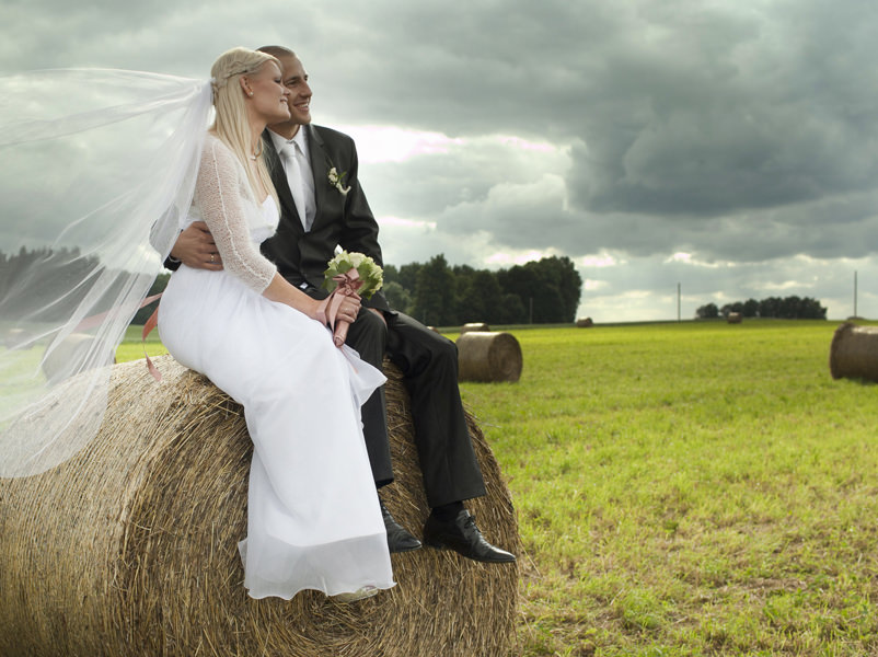 Braut und Bräutigam sitzen auf einem Heuballen